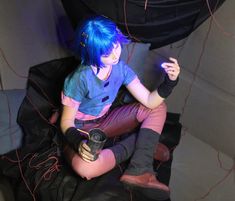 a woman with blue hair sitting on a chair