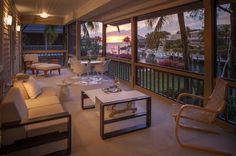 a living room filled with furniture next to a window covered in blinds and palm trees