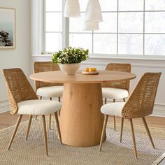 a dining room table with four chairs and a bowl of fruit on the center piece