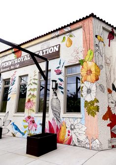 a building painted with flowers and birds on it's side, next to a street light