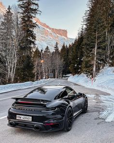 the black sports car is parked on the side of the road in front of some trees