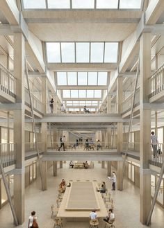 people are sitting at tables in the middle of a large room with high ceilings and glass windows