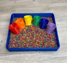 a blue tray filled with plastic cups and sprinkles