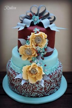 a three tiered cake with flowers on the top and bottom, sitting on a blue plate