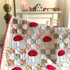 a quilted blanket with red and white polka dot designs on it in front of a fireplace