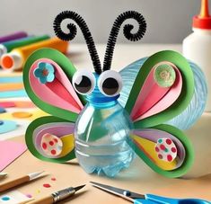 a butterfly made out of paper sitting on top of a table next to markers and pens