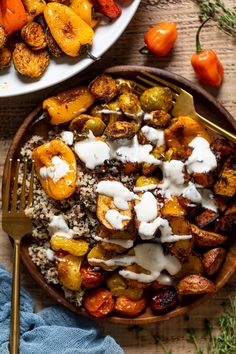 two plates filled with potatoes covered in ranch dressing next to a bowl of roasted vegetables