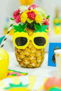 a pineapple with sunglasses on top of it sitting next to a card and some flowers