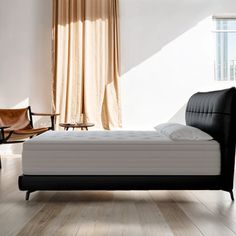 a bed sitting on top of a hard wood floor next to a chair and window