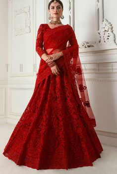 a woman in a red gown standing next to a white wall