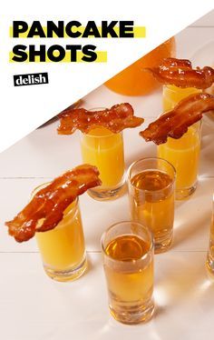 several shot glasses filled with orange juice and bacon shots