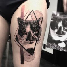 a black and white cat tattoo on the thigh, with a geometrical design behind it