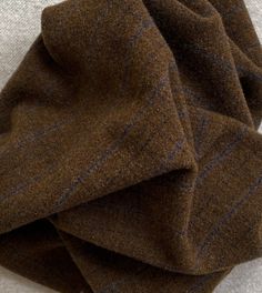 a pile of brown and blue striped wool fabric on top of a white table cloth