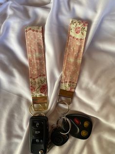 two car keys are sitting next to each other on a white sheet with pink flowers