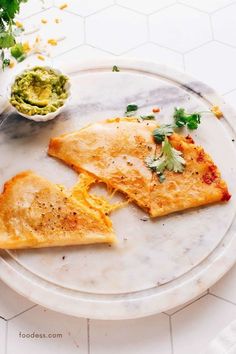 two pieces of pizza on a plate with guacamole