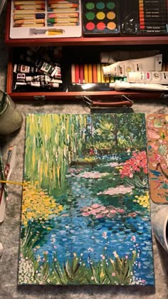 a painting with water lilies and other art supplies on the table next to it