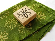 a wooden block with a flower on it sitting on top of green carpeted area