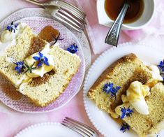 two plates with slices of cake on them next to a cup of tea and silverware