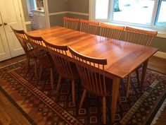 a dining room table with six chairs and a rug on the floor in front of it