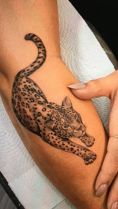 a woman's arm with a tattoo of a cheetah sitting on it