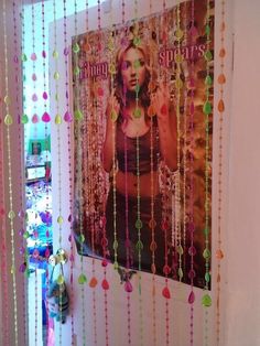 there is a poster on the wall with beads hanging from it's sides,