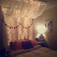 a bed with lights hanging from the ceiling and curtains over it's headboard