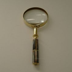 a magnifying glass on top of a gold colored metal object against a white wall