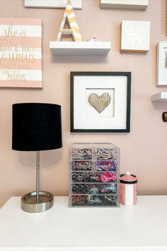 a white desk topped with a lamp next to a wall covered in pictures and other items