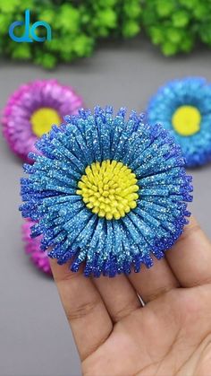 the small blue and yellow flower is being held in someone's hand with other flowers behind it