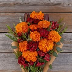 an orange and red bouquet sitting on top of a wooden table