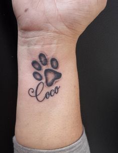 a dog paw with the word loco written on it's wrist and an arrow tattoo