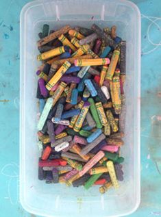 a container filled with crayons on top of a blue tablecloth covered floor