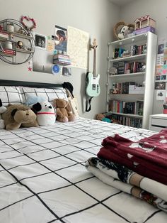 a bed with two stuffed animals sitting on top of it next to bookshelves