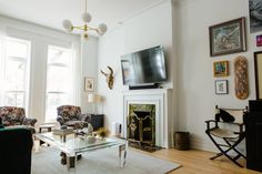 a living room filled with furniture and a flat screen tv mounted on the wall above a fire place