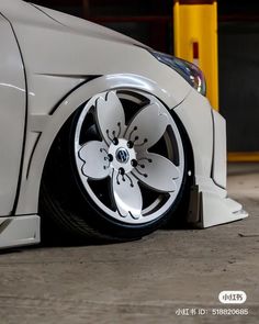 the front wheel of a white car with flowers painted on it's rims