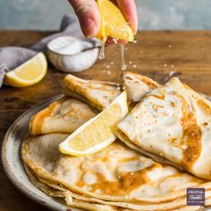 someone sprinkling lemon onto some pancakes on a plate