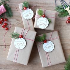 four wrapped presents tied with twine on top of a wooden table next to christmas decorations