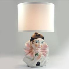 a ceramic figurine lamp with a white shade