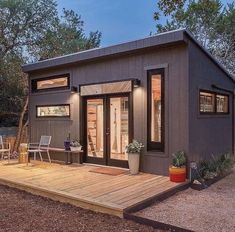 a small house with a deck in the middle of it and lots of windows on each side