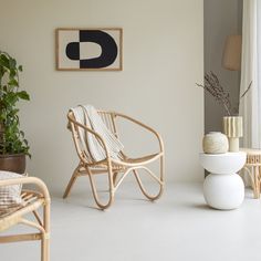 a chair and table in a room with white walls, potted plants and pictures on the wall