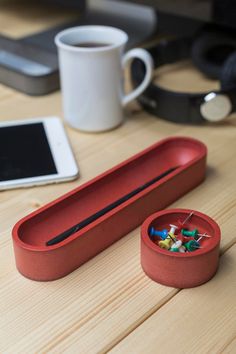 a red container filled with lots of different things next to a cup and cell phone