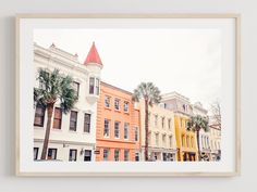 a framed photograph of buildings with palm trees in the foreground