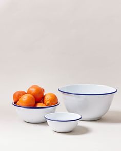 three bowls with oranges in them sitting next to each other on a white surface