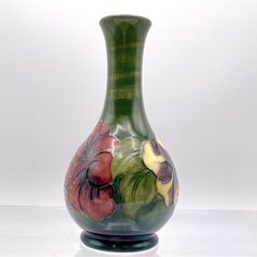 a green vase with flowers painted on it