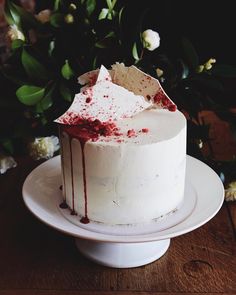 a cake with white frosting and red sprinkles sitting on a plate