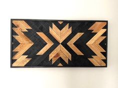 a wooden wall hanging on the side of a white wall with an arrow design in it