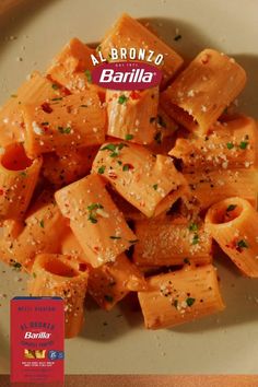 a white plate topped with pasta covered in parmesan cheese and seasoning next to a bottle of wine