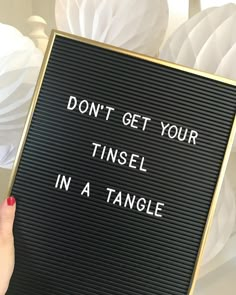 a woman holding up a sign that says don't get your tinsel in a tangle