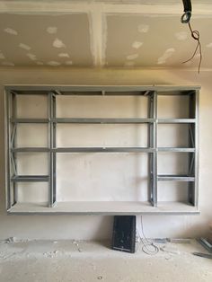 an unfinished room with shelves and wires in the ceiling, being built into the wall