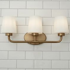 three light bathroom fixture with white glass shades on the top and bottom half of it